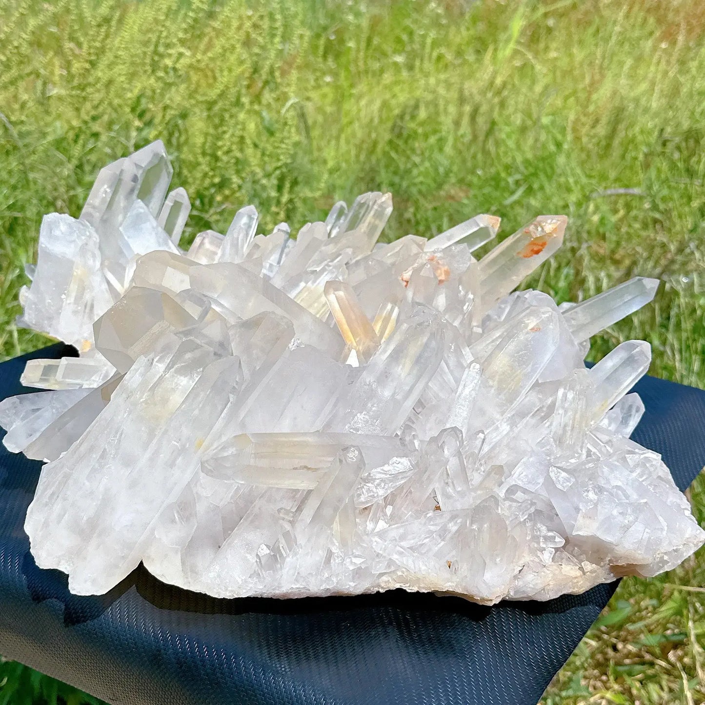 brazilian quartz crystal cluster glowing in sunlight on black cloth backdrop - clearquartzshop