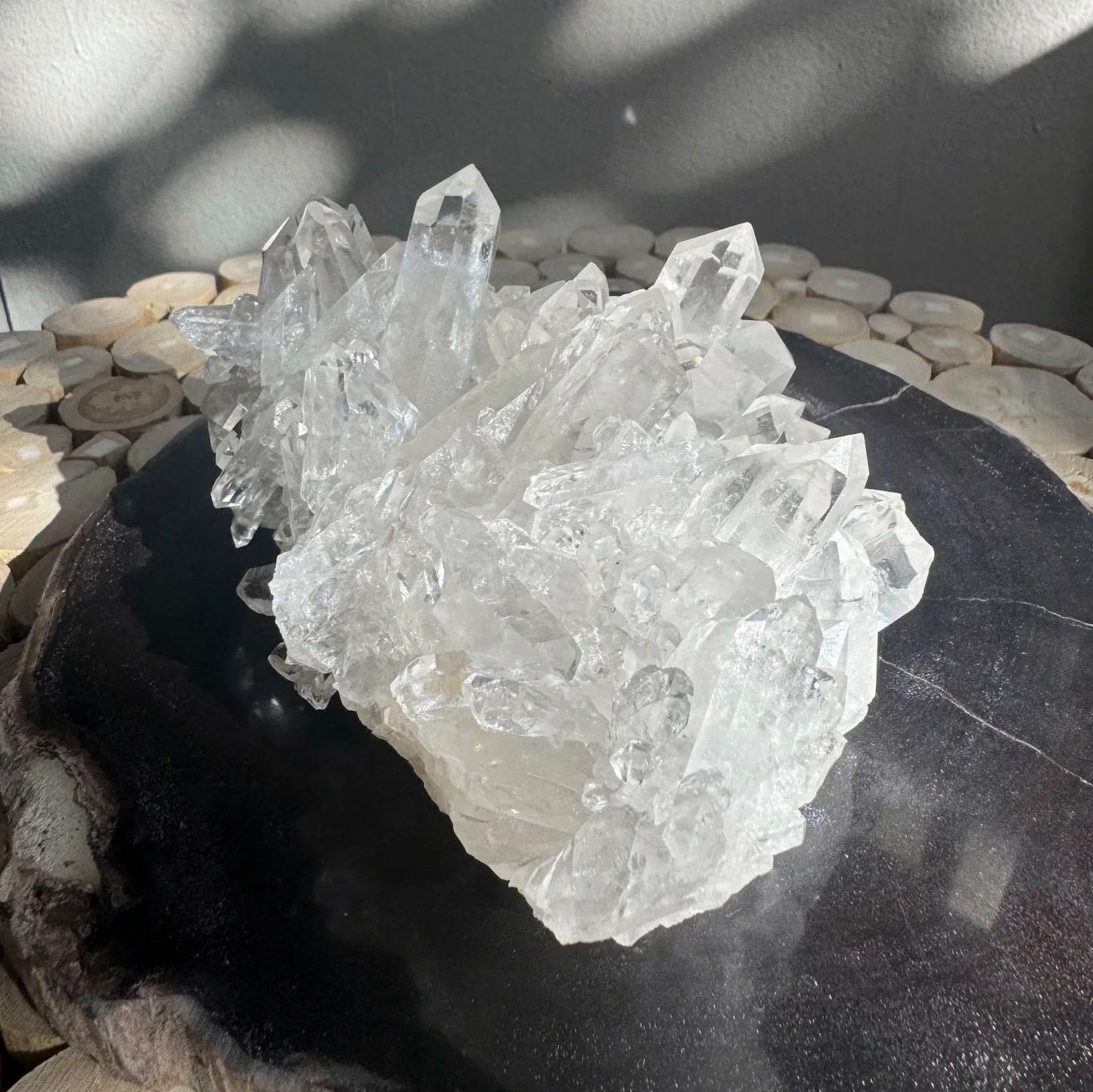 large clear quartz crystal cluster on black surface, displayed under natural light - healing crystal from clearquartzshop