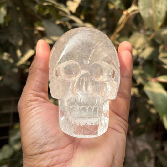 front view of 1kg hand-carved himalayan clear quartz skull held in hand outdoors - clearquartzshop